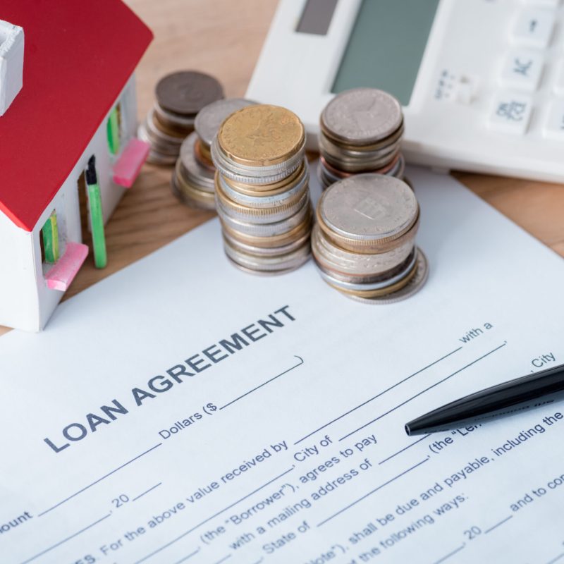 loan agreement, house model, calculator, silver and golden coins on wooden surface